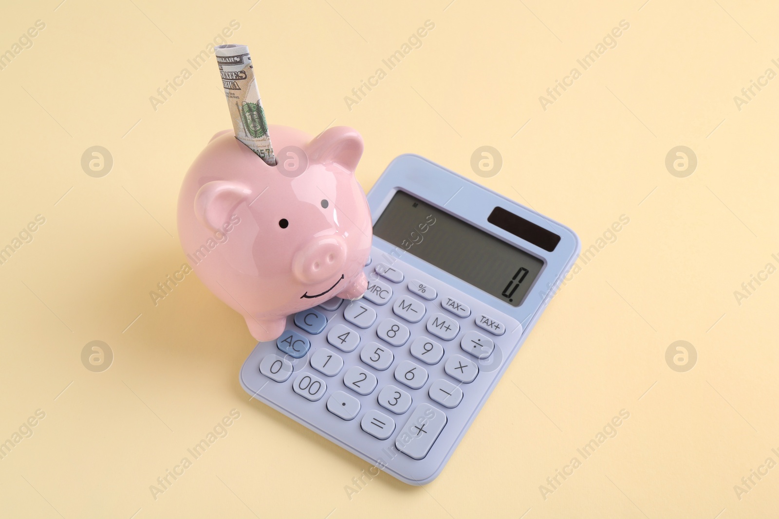 Photo of Financial savings. Piggy bank, dollar banknote and calculator on beige background