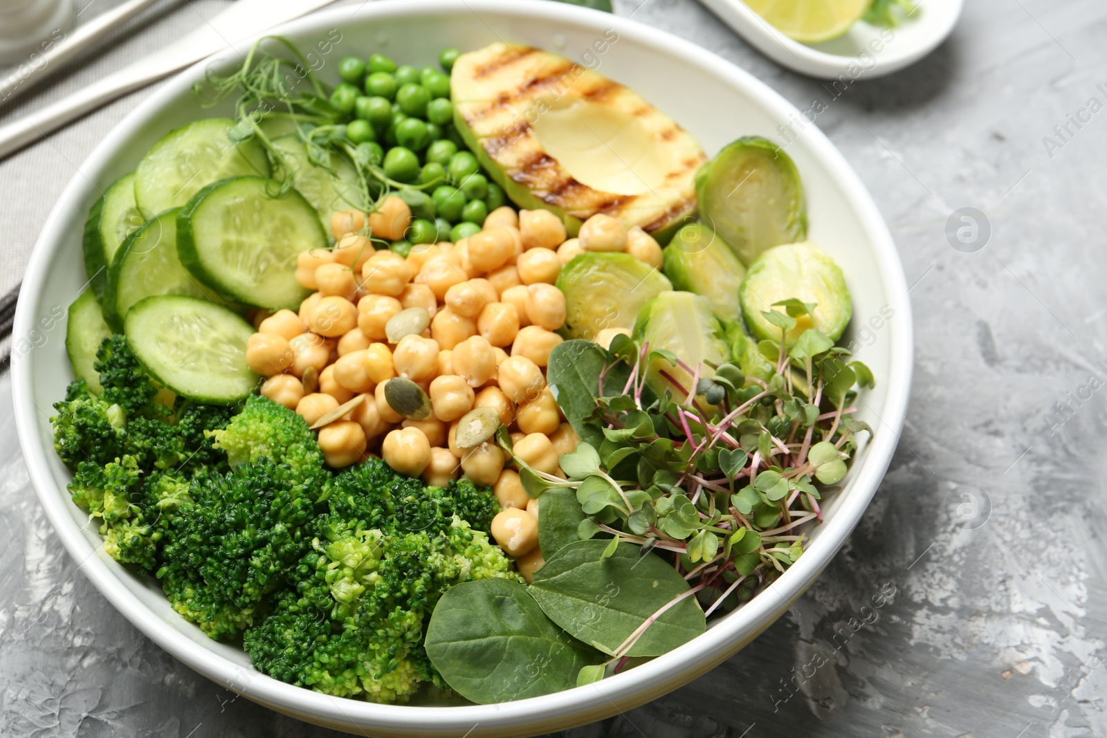 Photo of Healthy meal. Tasty vegetables and chickpeas in bowl on grey table, closeup