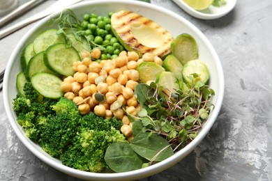 Healthy meal. Tasty vegetables and chickpeas in bowl on grey table, closeup