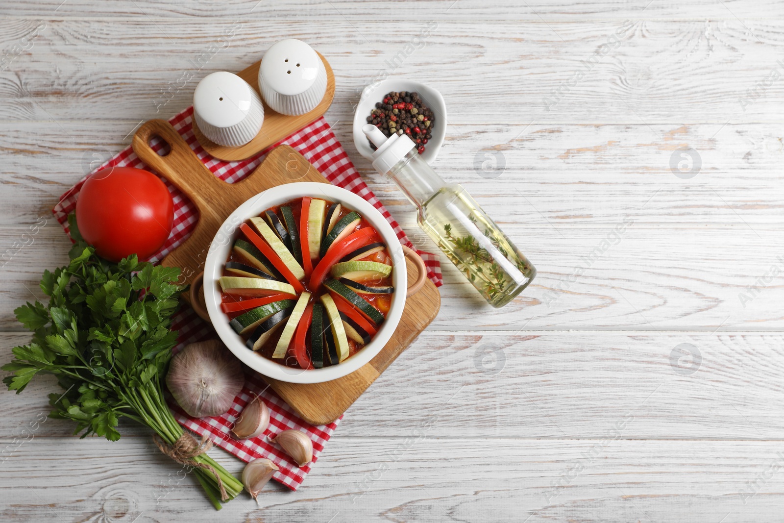 Photo of Cooking delicious ratatouille. Dish with different fresh cut vegetables on white wooden table, flat lay. Space for text