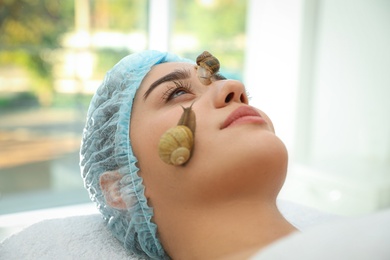 Young woman receiving snail facial massage in spa salon, closeup