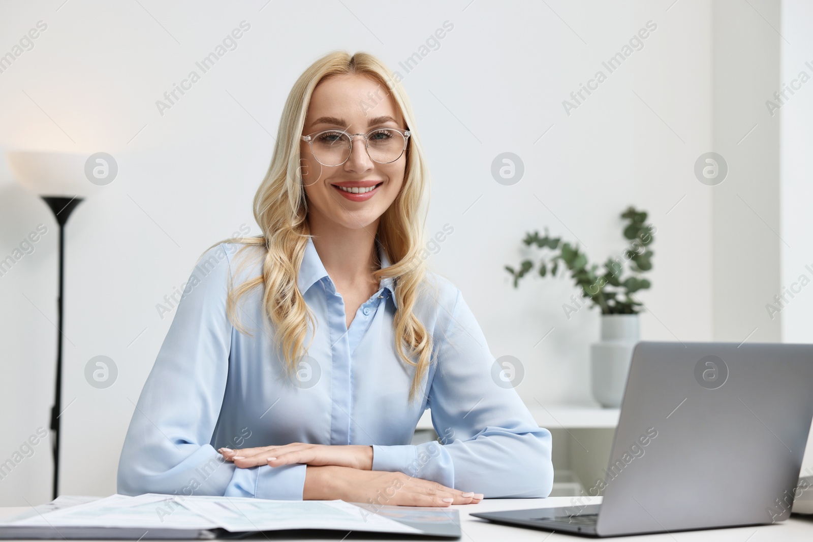Photo of Happy secretary at table with laptop in office