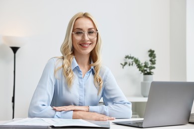 Happy secretary at table with laptop in office