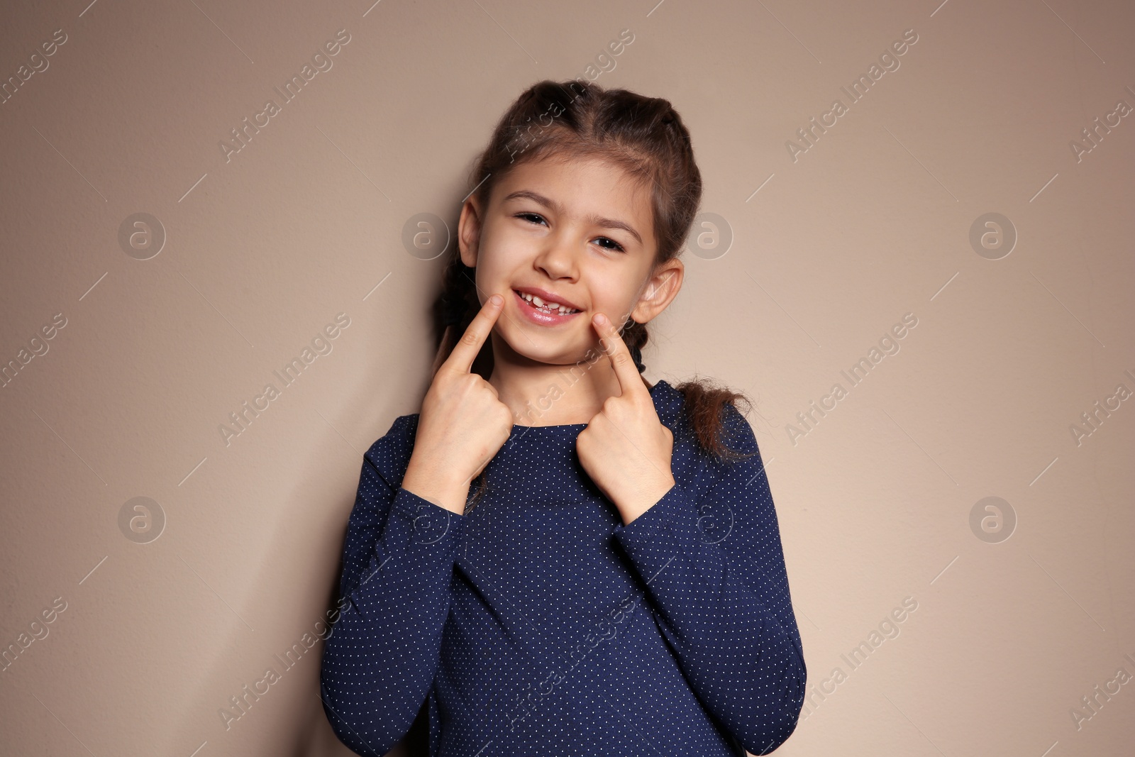 Photo of Little girl showing LAUGH gesture in sign language on color background