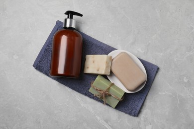 Photo of Soap bars and bottle dispenser on grey marble table, top view