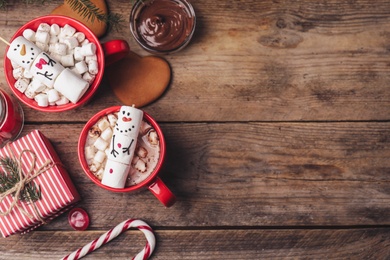 Photo of Flat lay composition with marshmallow snowmen on wooden table. Space for text