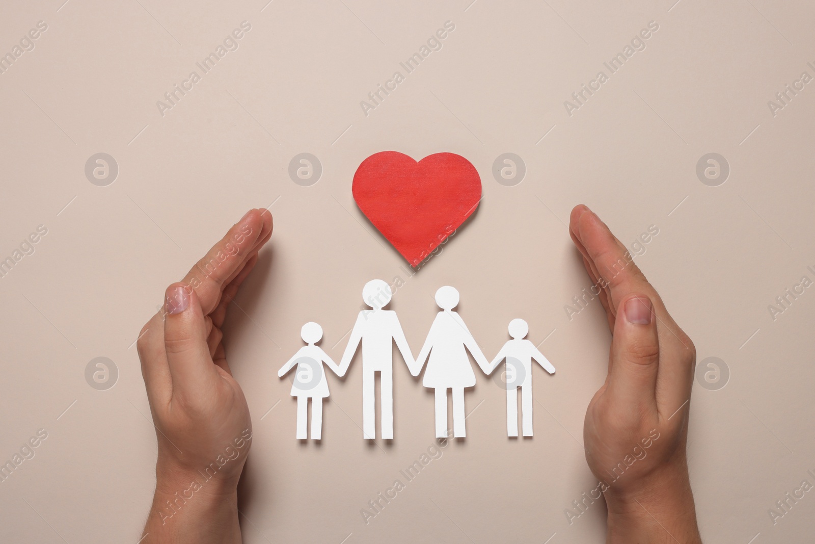 Photo of Man protecting paper family figures and red heart on beige background, top view. Insurance concept