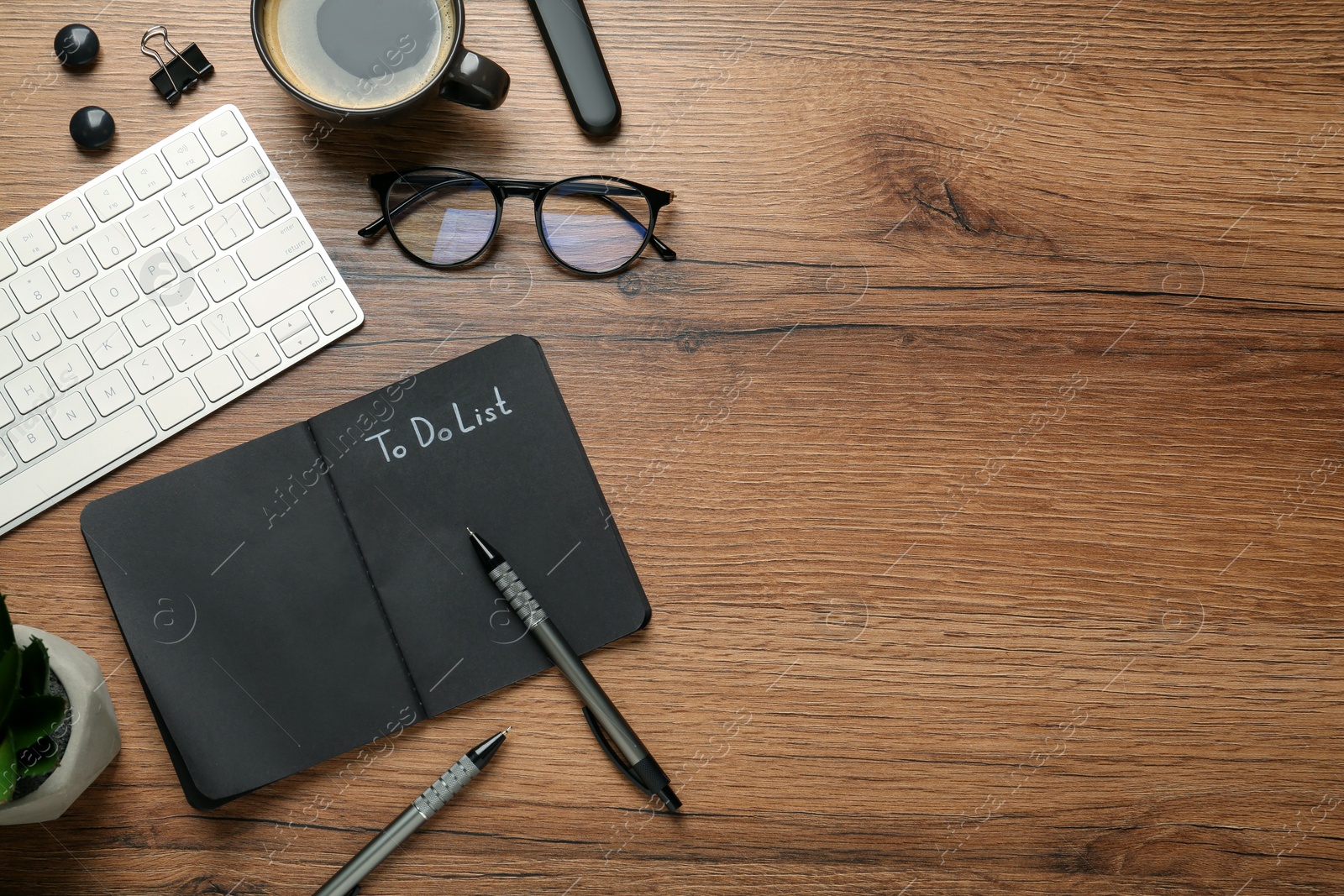 Photo of Flat lay composition with unfilled To Do list in notepad, cup of coffee and computer keyboard on wooden table, space for text