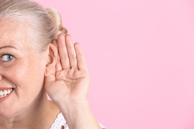 Photo of Mature woman with hearing problem on color background, closeup. Space for text