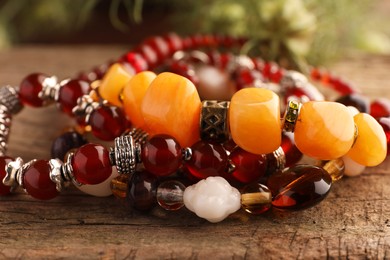 Beautiful bracelets with gemstones on wooden surface, closeup