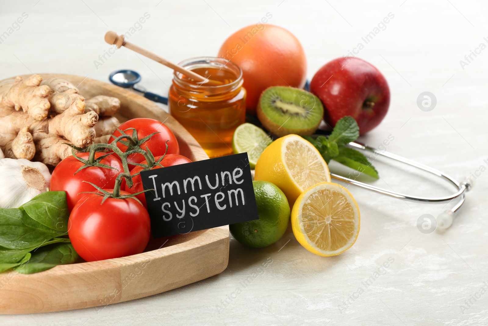 Photo of Card with phrase Immune System, stethoscope and fresh products on light table