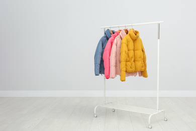 Rack with warm jackets in room. Space for text