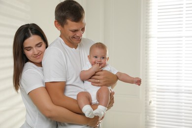 Photo of Happy family. Couple with their cute baby near window indoors