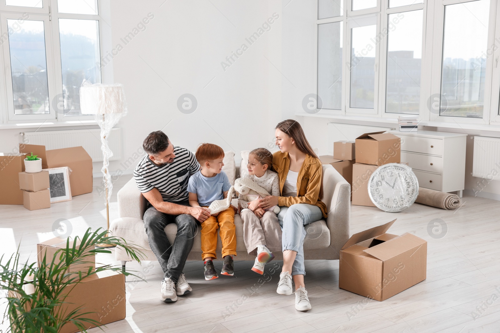 Photo of Happy family sitting on couch in new apartment. Moving day