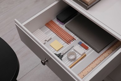 Office supplies in open desk drawer indoors. above view