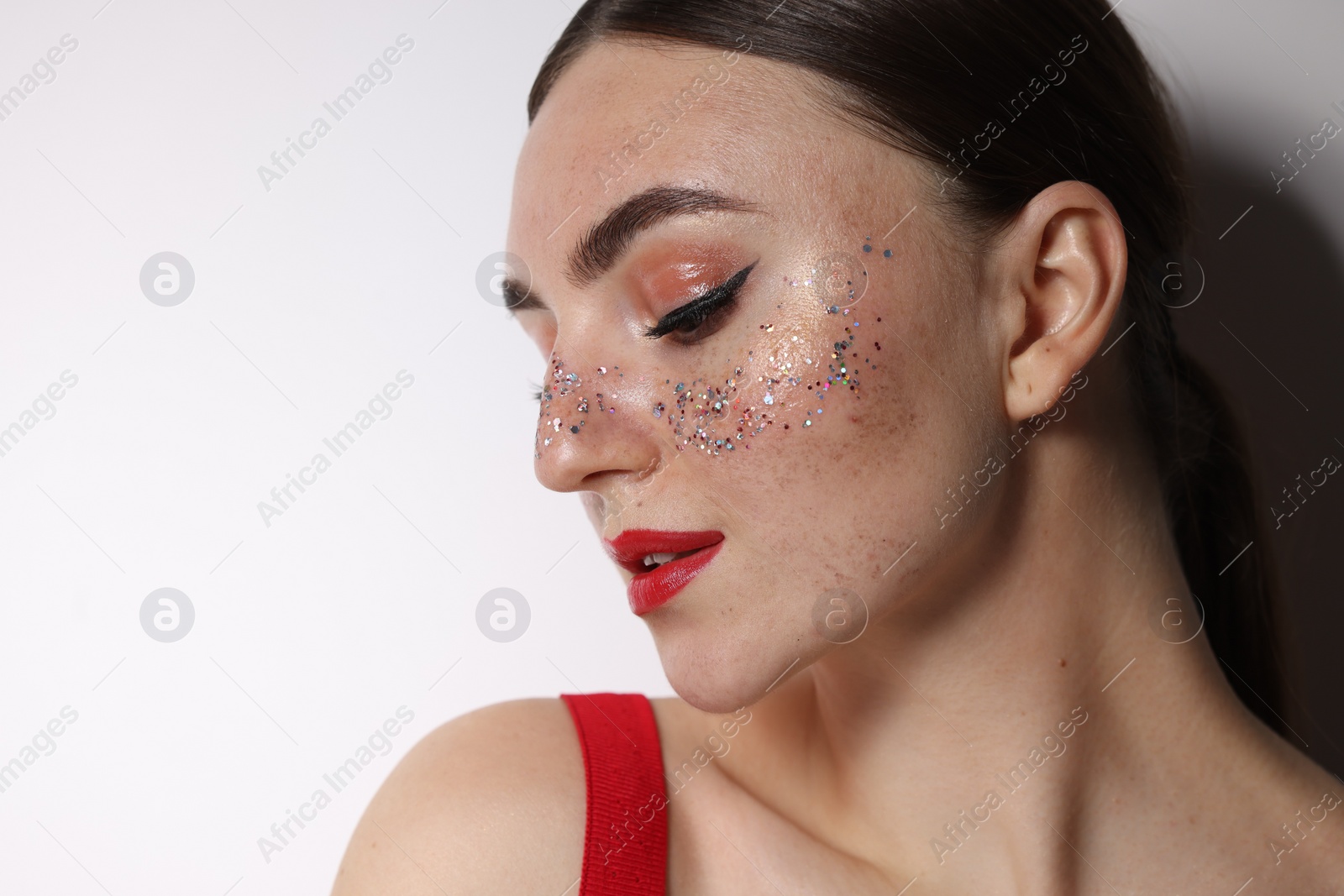 Photo of Beautiful woman with glitter freckles on light background, closeup. Space for text