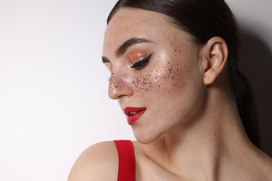 Photo of Beautiful woman with glitter freckles on light background, closeup. Space for text