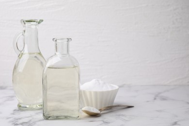 Photo of Vinegar and baking soda on white marble table, space for text