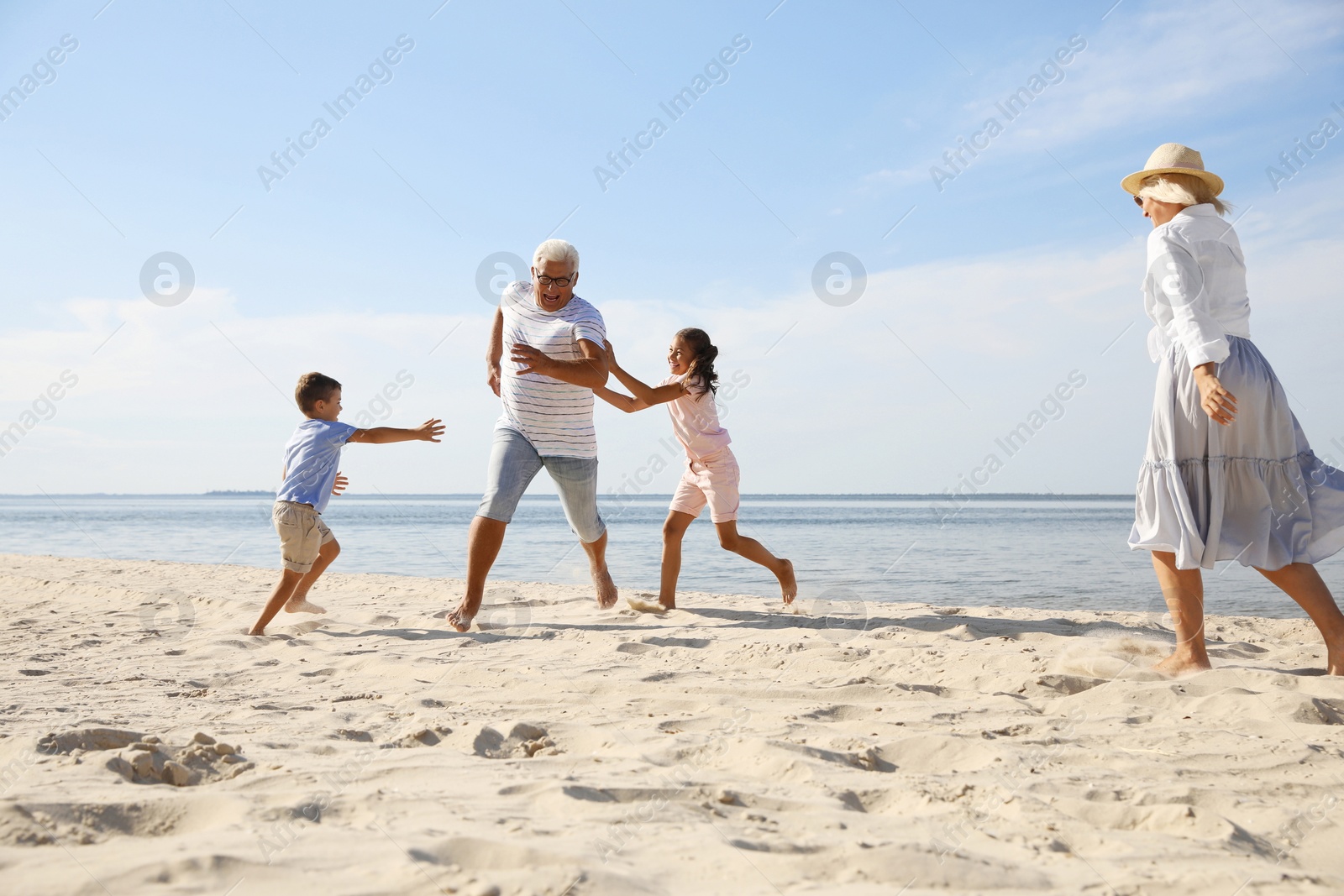 Photo of Cute little children with grandparents spending time together on sea beach