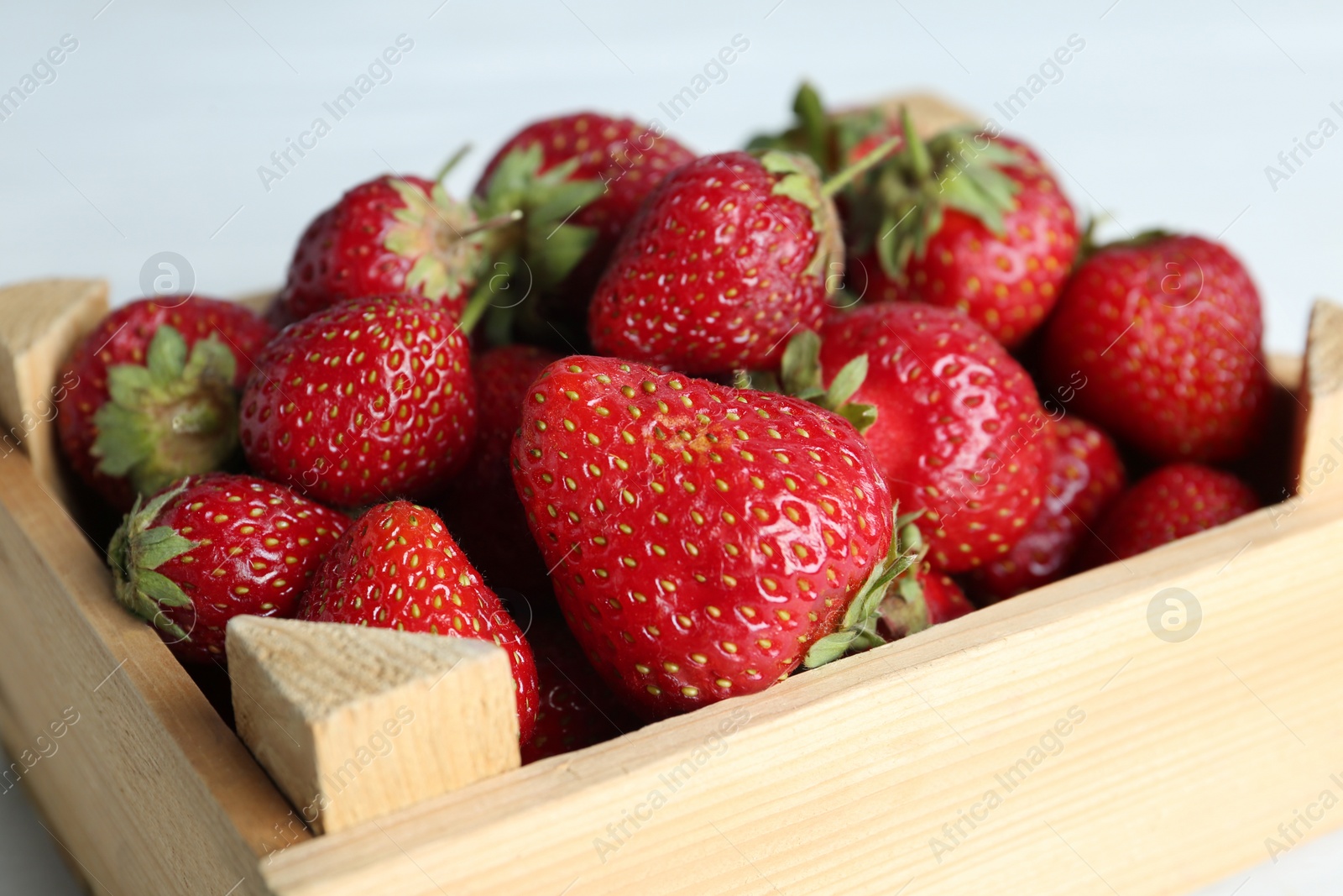 Photo of Delicious ripe strawberries in wooden crate, closeup