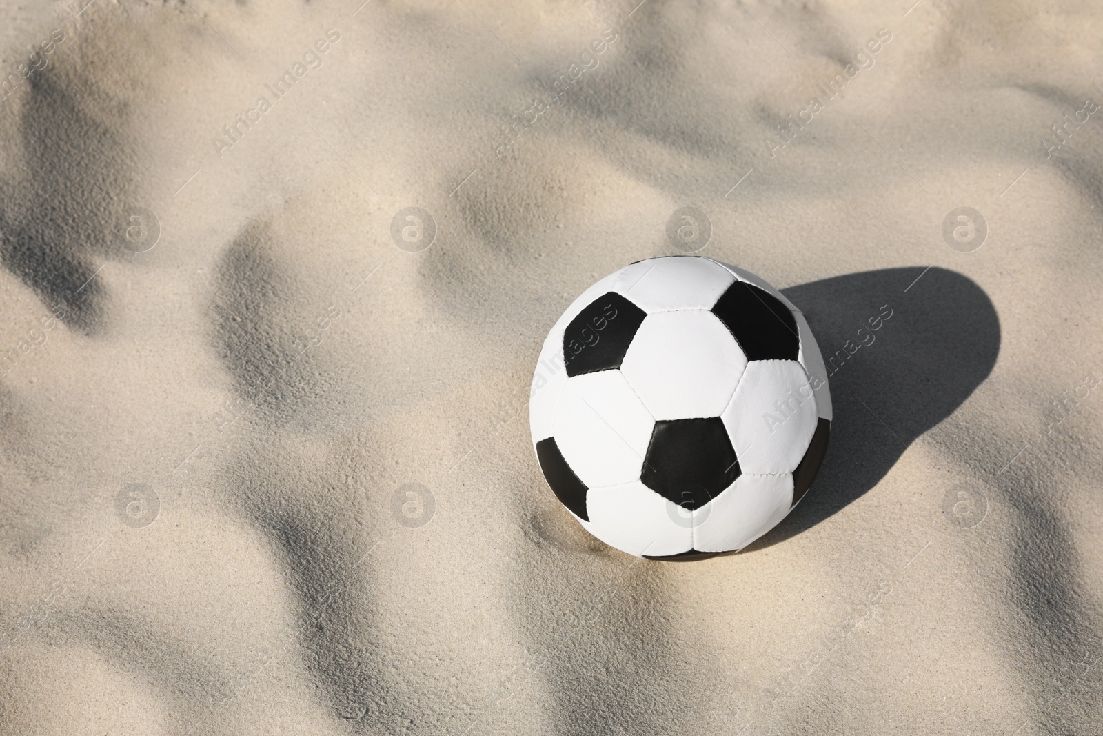 Photo of Soccer ball on sand, space for text. Football equipment