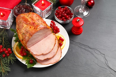 Photo of Delicious Christmas ham served with garnish on dark table, above view