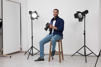 Photo of Young professional photographer with camera in modern photo studio