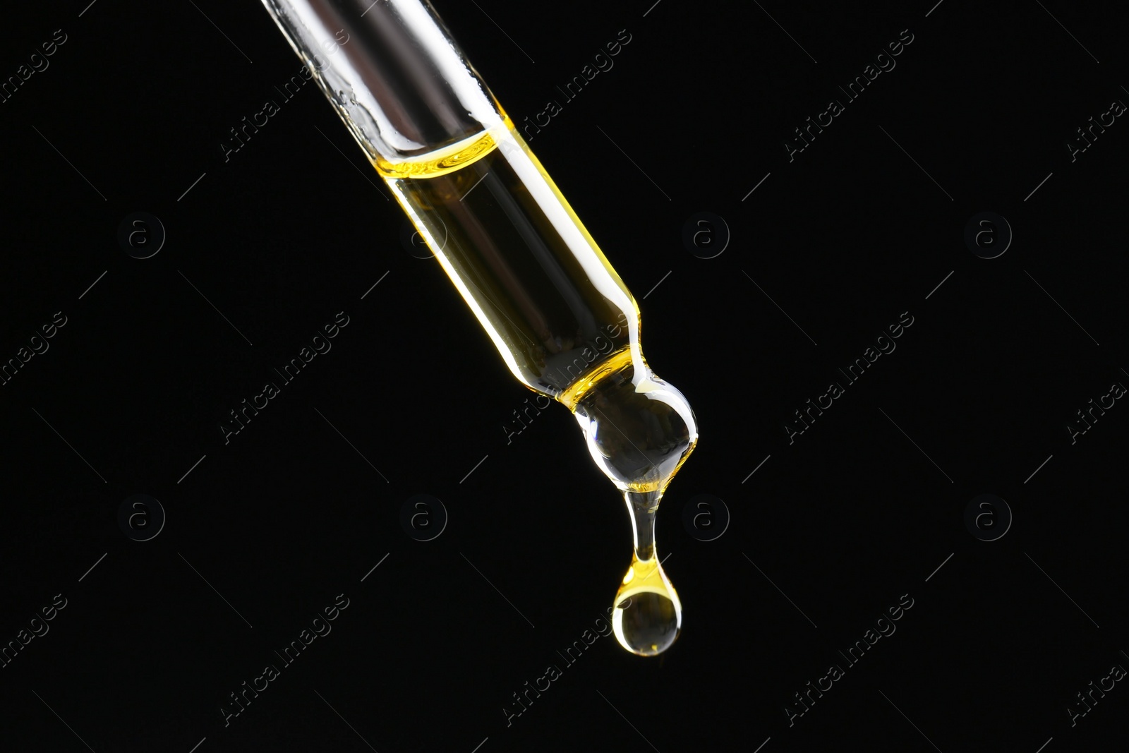 Photo of Dripping tincture from pipette on black background, closeup