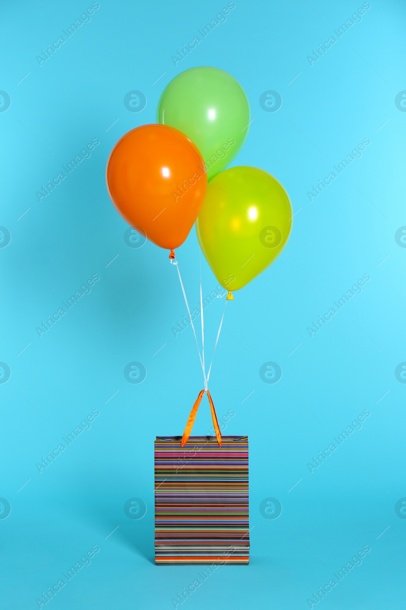 Photo of Paper bag with bright air balloons on color background