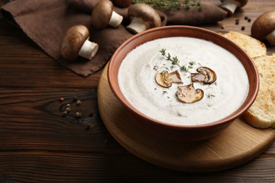 Fresh homemade mushroom soup in ceramic bowl on wooden table. Space for text