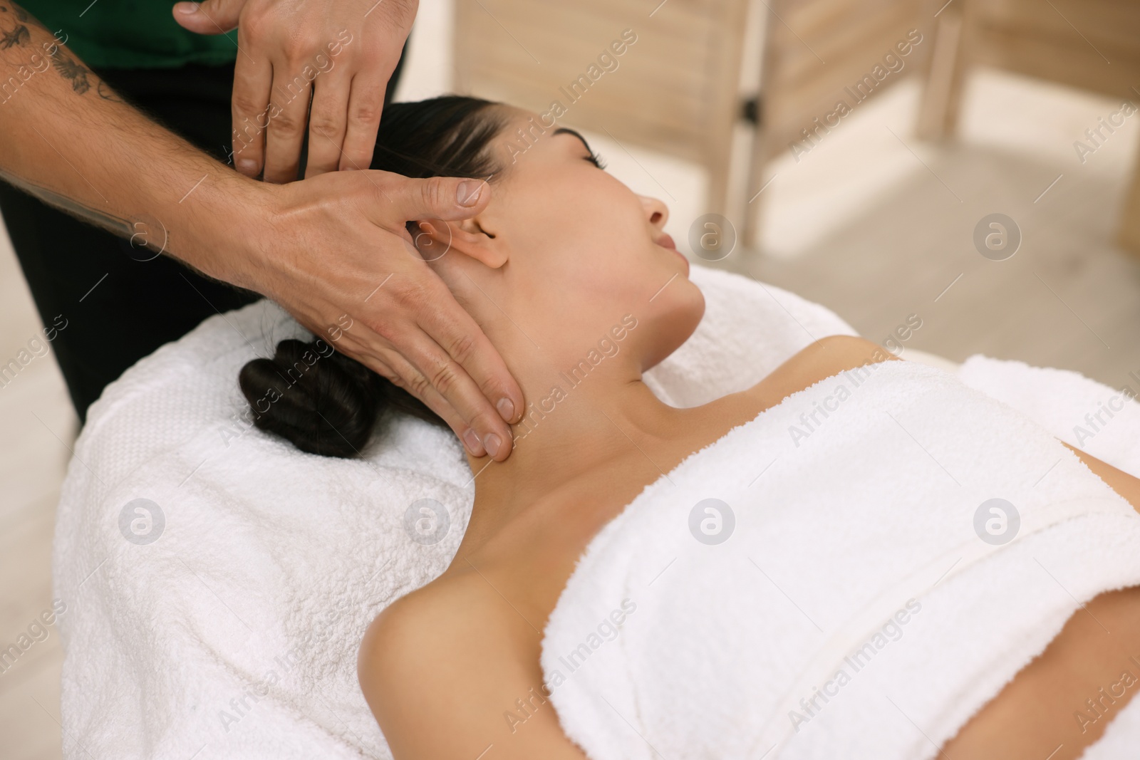 Photo of Woman receiving professional neck massage on couch indoors