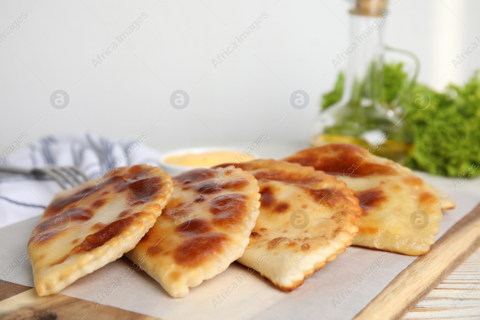 Photo of Delicious fried chebureki on white wooden table