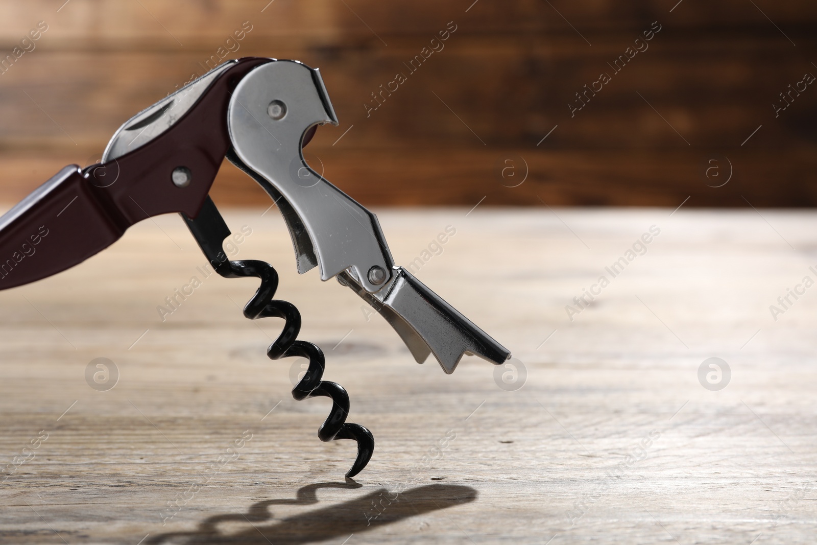 Photo of One corkscrew (sommelier knife) on wooden table, closeup. Space for text