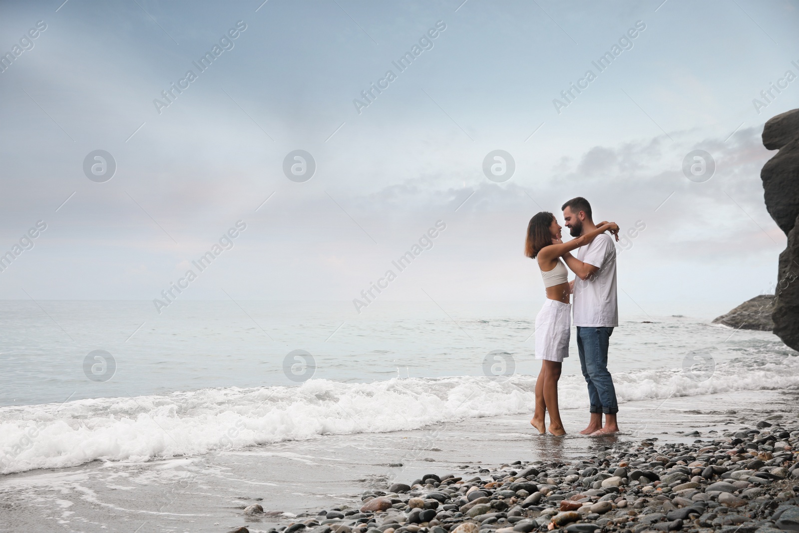 Photo of Happy young couple on beach near sea. Space for text