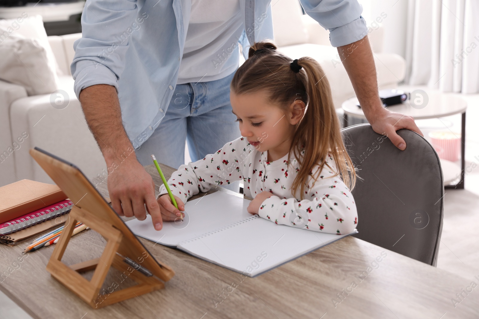 Photo of Father helping his daughter with homework using tablet at home