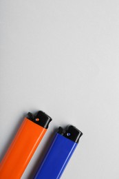 Photo of Stylish small pocket lighters on white background, flat lay. Space for text