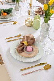 Festive Easter table setting with painted eggs, burning candles and yellow tulips
