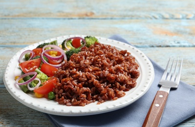 Photo of Plate of boiled brown rice with vegetables served on table