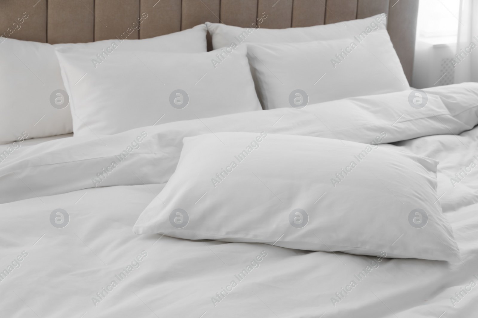 Photo of Many soft pillows and blanket on large comfortable bed indoors