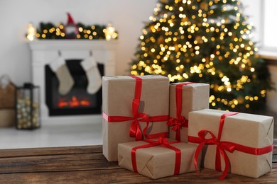 Many different gift boxes on wooden table against blurred festive lights in living room, space for text. Christmas presents