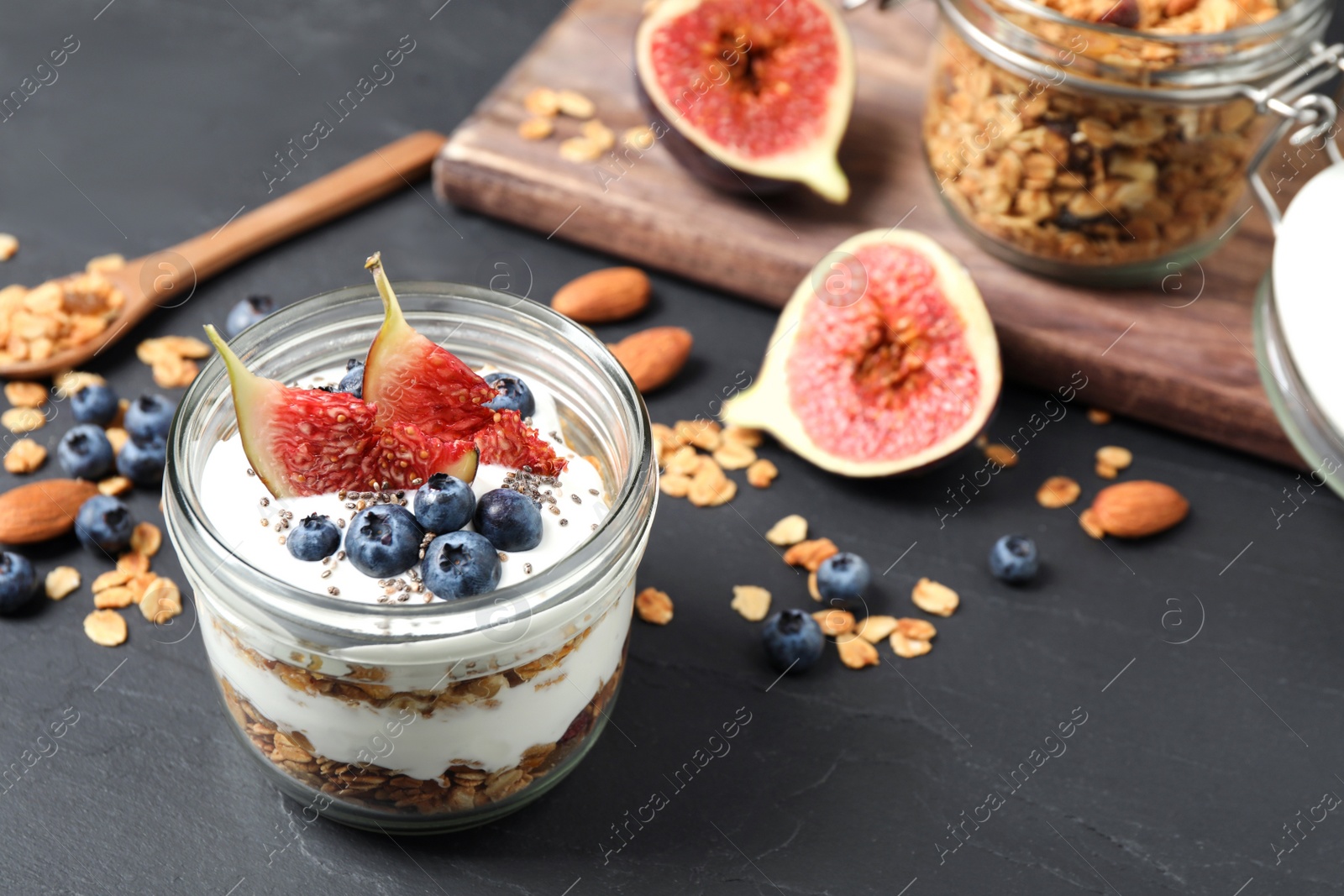 Photo of Tasty homemade granola dessert on dark grey table. Healthy breakfast