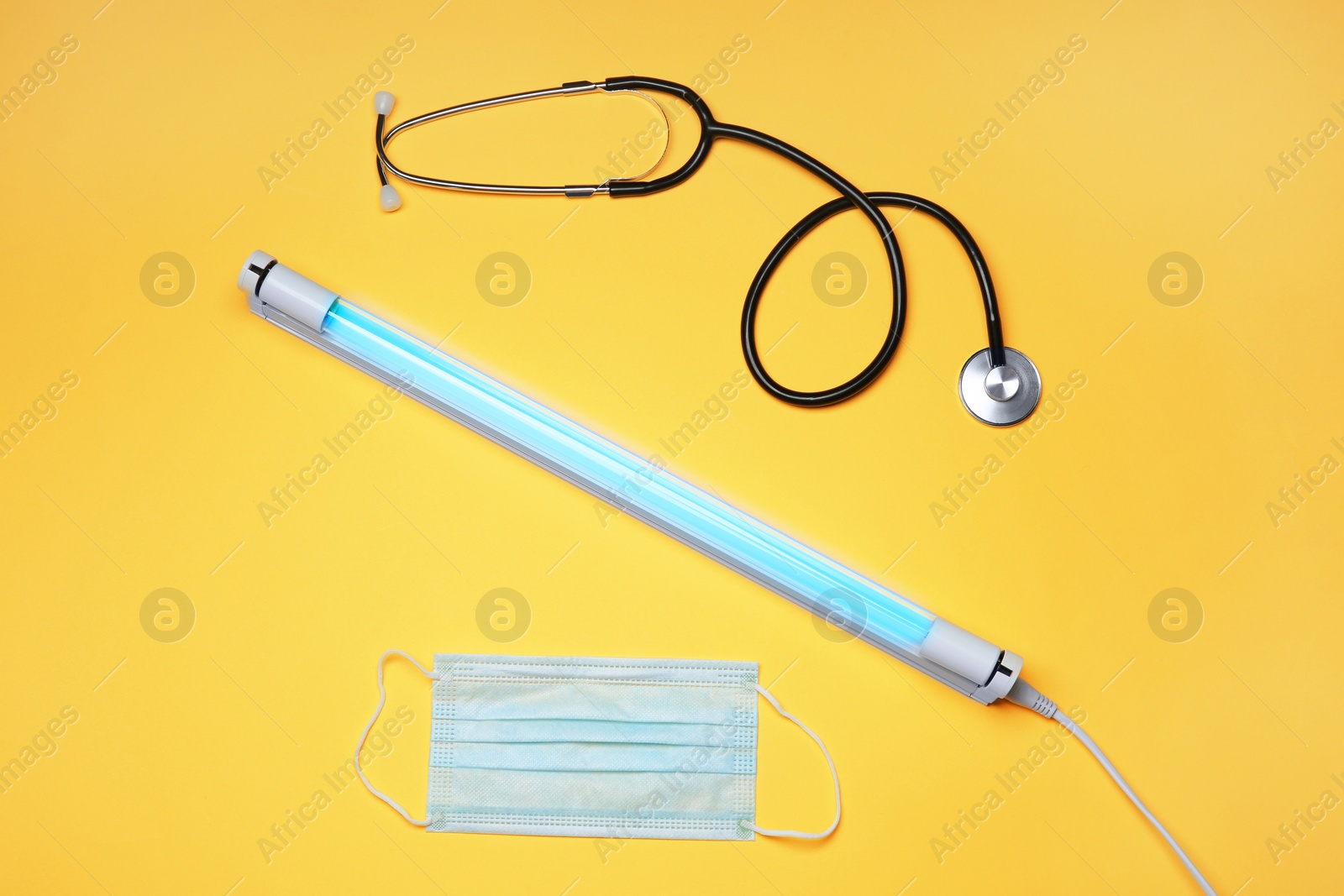 Photo of Flat lay composition with ultraviolet lamp on yellow background