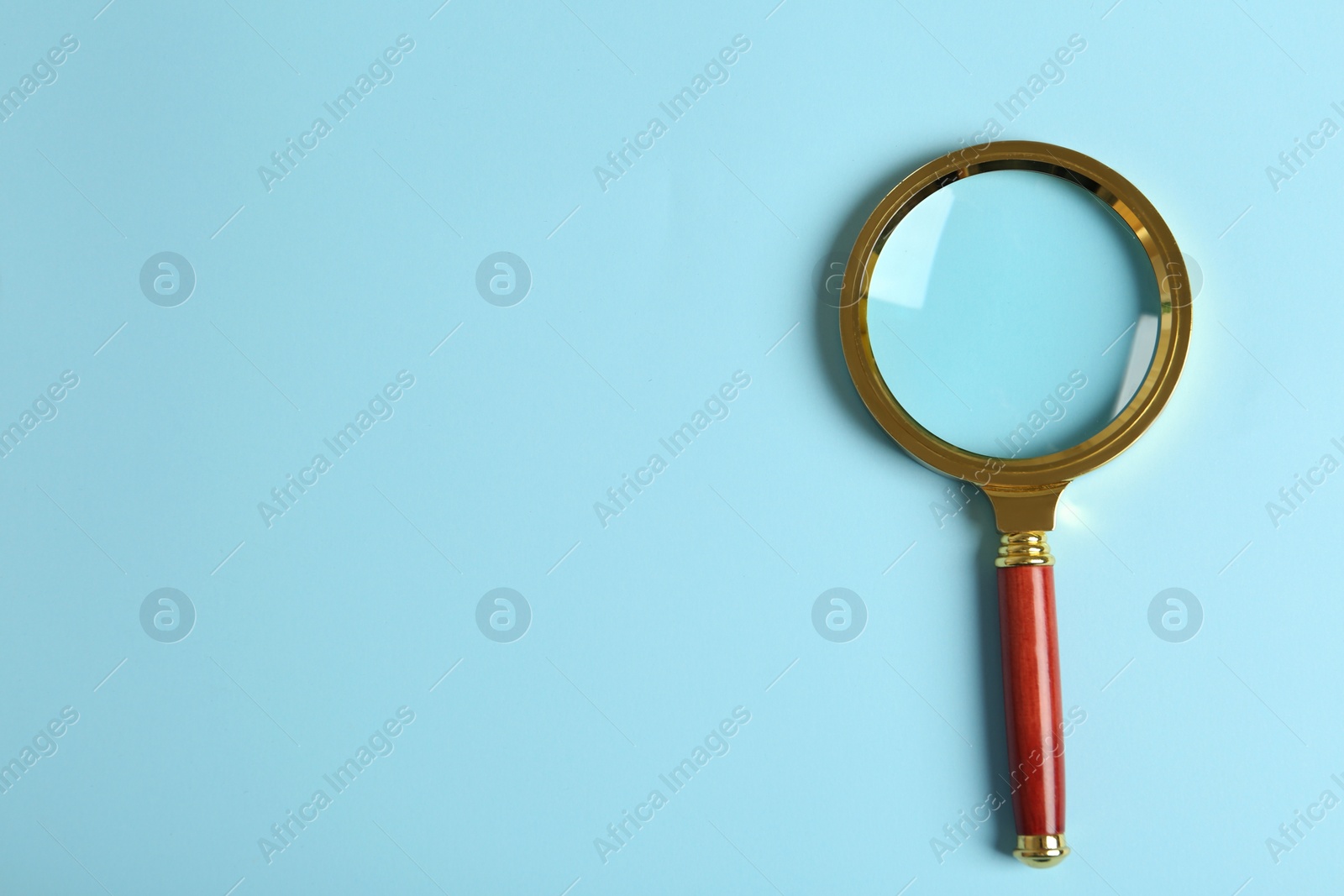 Photo of Top view of magnifying glass on light blue background, space for text. Search concept