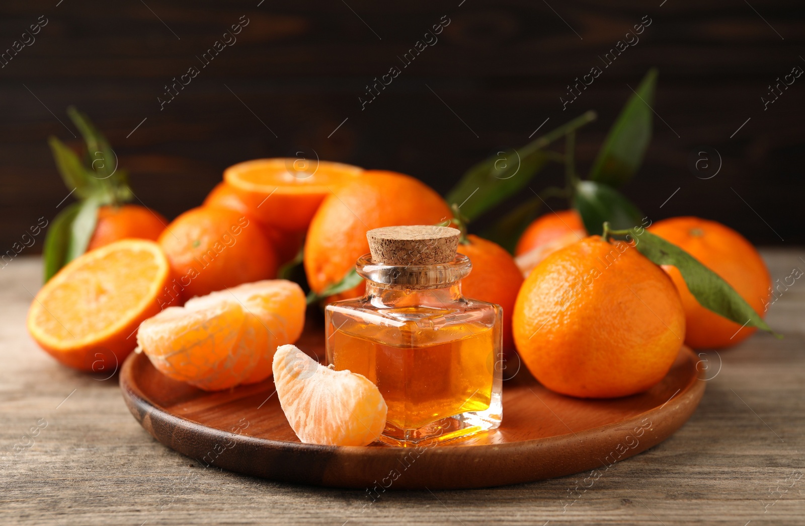 Photo of Bottle of tangerine essential oil and fresh fruits on wooden table