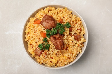 Photo of Bowl with delicious rice pilaf on light background, top view