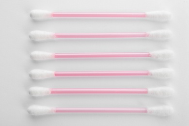 Pink plastic cotton swabs on white background, top view