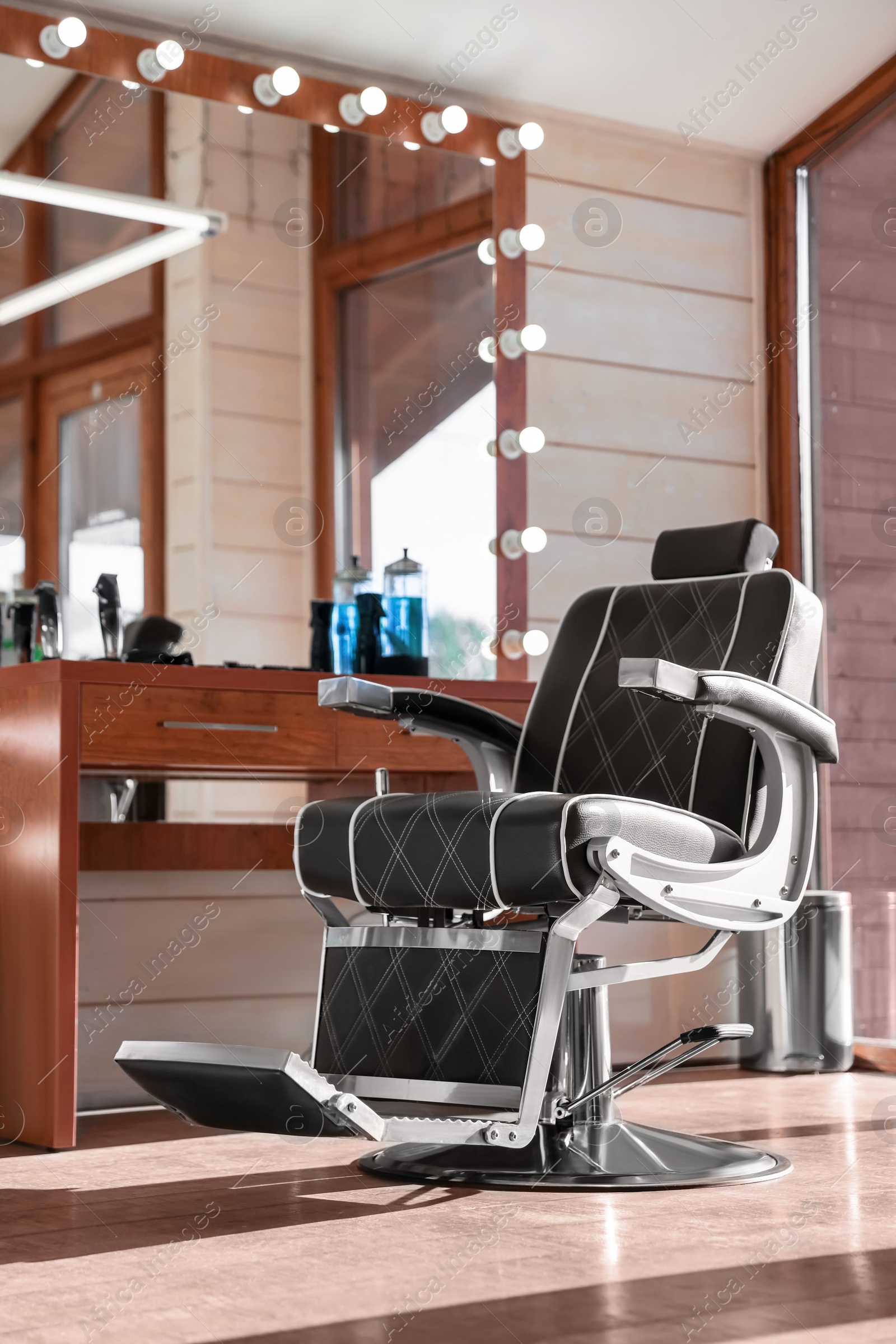 Photo of Stylish hairdresser's workplace with professional armchair and large mirror in barbershop. Interior design