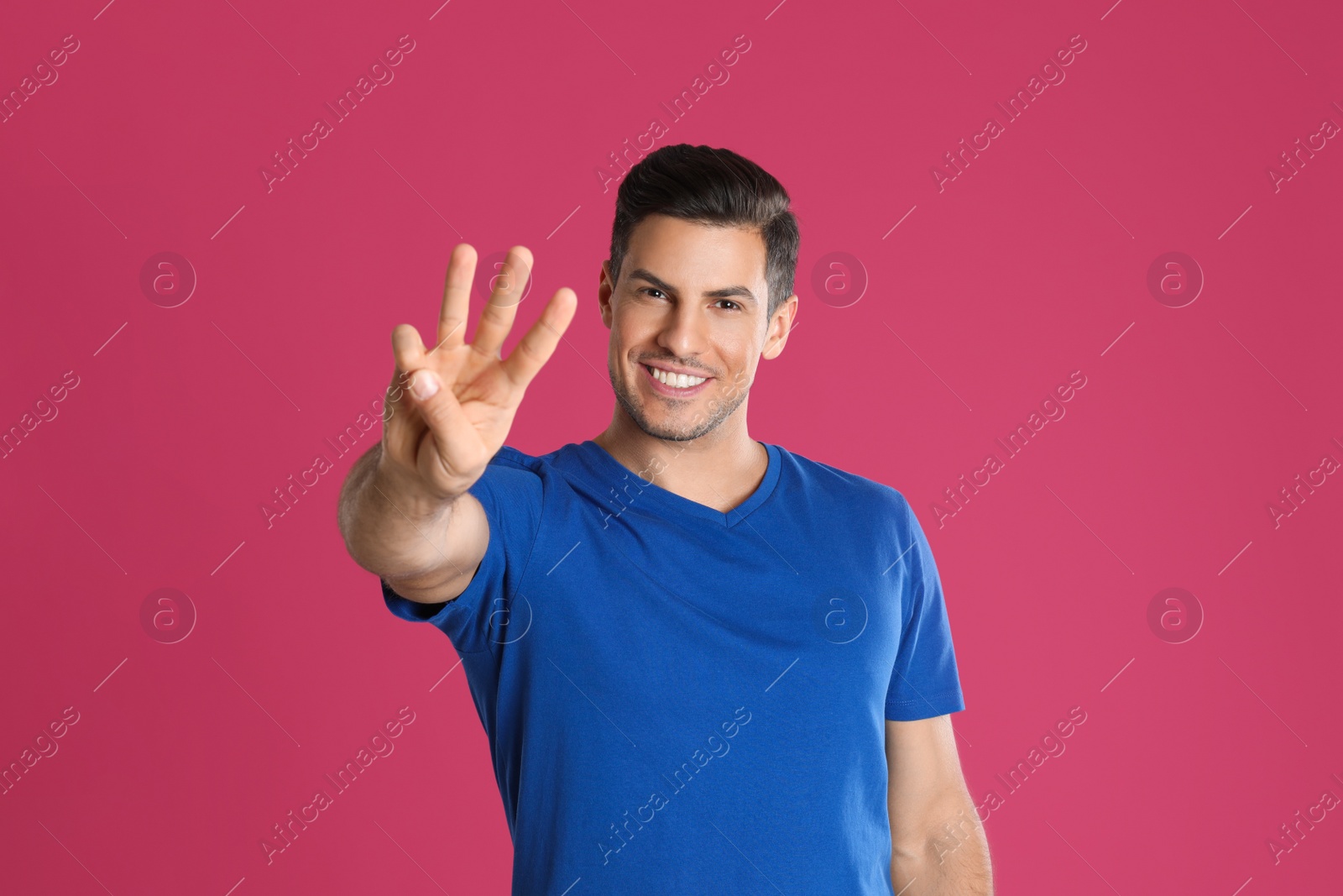 Photo of Man showing number three with his hand on pink background