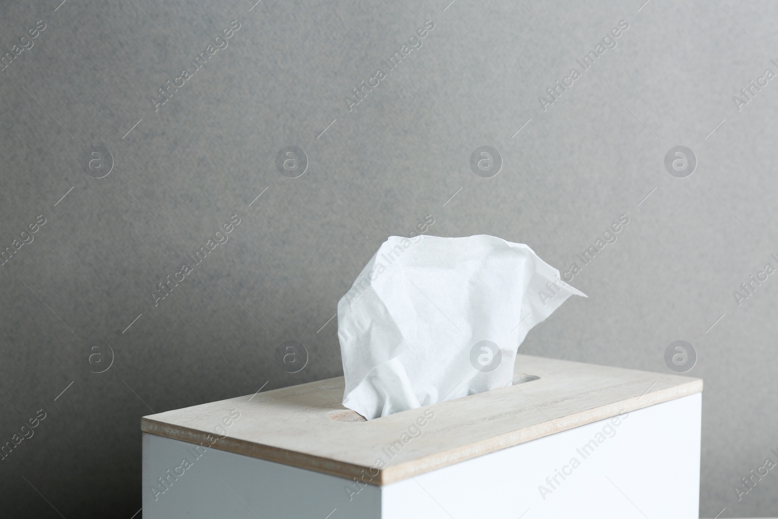 Photo of Holder with paper tissues on grey background