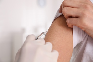 Doctor vaccinating woman against Covid-19 in clinic, closeup